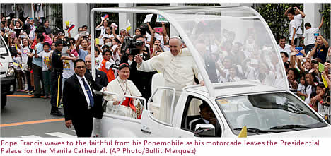 Pope Francis waves to the faithful from his Popemobile as his motorcade leaves the Presidential Palace for the Manila Cathedral. (AP Photo/Bullit Marquez)